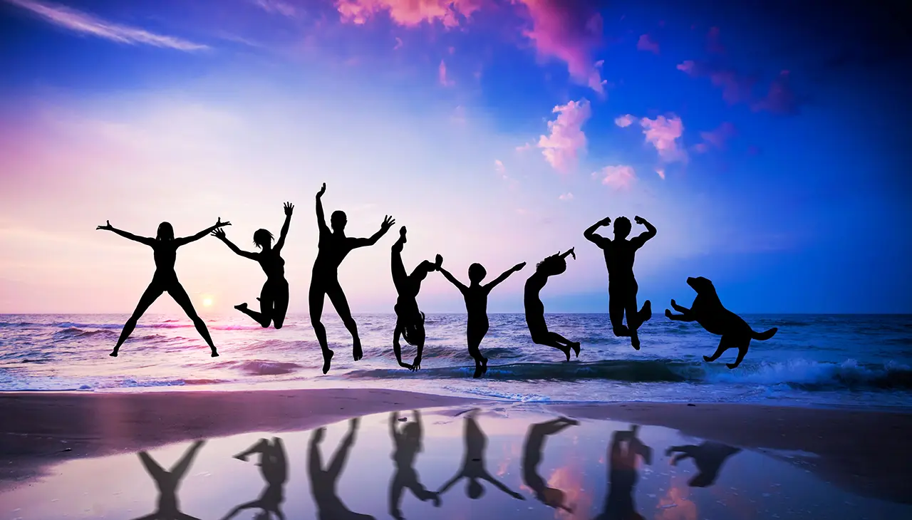 Silhouettes of eight people and a dog jump joyfully on a beach at sunset. The vibrant sky mirrors their energetic scene, reflecting the lively effects of neurofeedback in the vivid colors and playful movement on the wet sand. - The Parker Group Silhouettes of eight people and a dog jump joyfully on a beach at sunset. The vibrant sky mirrors their energetic scene, reflecting the lively effects of neurofeedback in the vivid colors and playful movement on the wet sand.